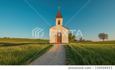Whitewashed church stands among fields beneath clear sky with gentle breeze 130494915
