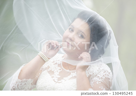 The fat bride hid in a wedding veil against the backdrop of nature. 130495245