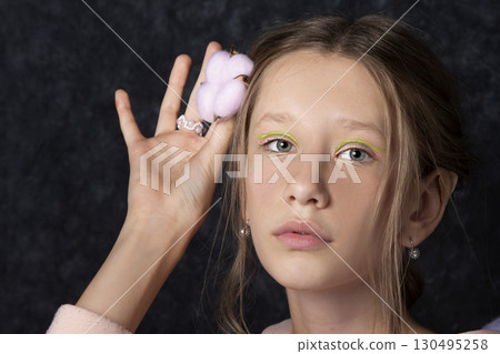 Portrait of a teenage girl in pink clothes on a dark background. 130495258