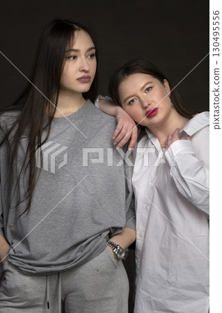 Two beautiful girls-friends on a dark background. 130495556