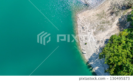 Serene shoreline embraces turquoise waters under a bright summer sun in a tranquil natural oasis 130495873