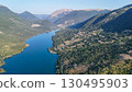Serene panoramic view of a tranquil lake surrounded by lush hills at sunrise in a picturesque valley 130495903
