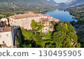 Charming village perched on a hillside overlooking tranquil waters in Italy during late afternoon light 130495905