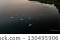 Calm waters cradle sailboats under the twilight sky at a serene lakeside retreat 130495906