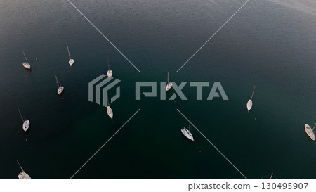 Serenity of anchored sailboats in calm waters during the golden hour near a peaceful coastline 130495907