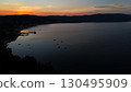 Breathtaking sunset over tranquil waters and distant hills captures the serene beauty of coastal life in late evening light 130495909