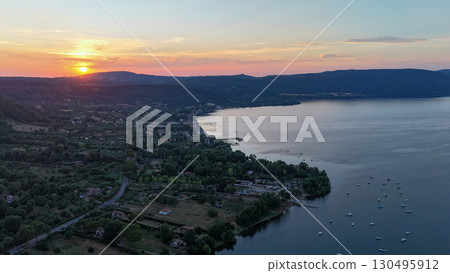 Breathtaking sunset over tranquil lake with serene hills in the background revealing nature's beauty and serenity 130495912