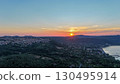Vibrant sunset illuminates the hills and waterfront village in tranquil evening sky over lush green landscape 130495914
