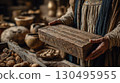 An ancient figure holds a wooden box engraved with mysterious symbols, surrounded by historical artifacts and pottery in a dimly lit setting evoking ancient civilizations 130495955