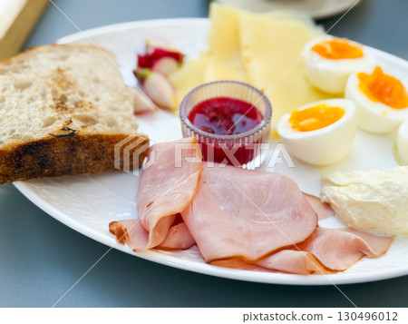 A breakfast plate with ham, cheese, eggs, bread, and jam served with tea. Nutrition, lifestyle, and dining culture illustrate morning meal, tradition, and balanced food choices. A breakfast plate with ham, cheese, eggs, bread, and jam served with tea. Nutrition, lifestyle, and dining culture illustrate morning meal, tradition, and balanced food choices. 130496012