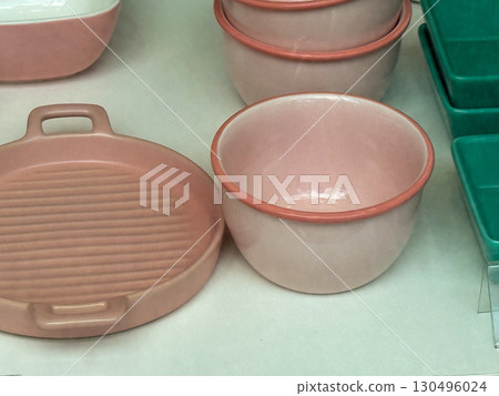Ceramic tableware in soft pink and green tones displayed on a shop shelf. Kitchen equipment, dining utensils, and consumer goods symbolize household lifestyle and everyday domestic aesthetics. Ceramic tableware in soft pink and green tones displayed on a shop shelf. Kitchen equipment, dining utensils, and consumer goods symbolize household lifestyle and everyday domestic aesthetics. 130496024