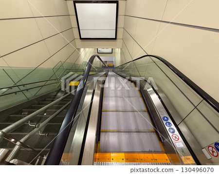 Downward escalator in modern airport interior. Transportation, travel and mobility infrastructure in public facilities. Downward escalator in modern airport interior. Transportation, travel and mobility infrastructure in public facilities. 130496070
