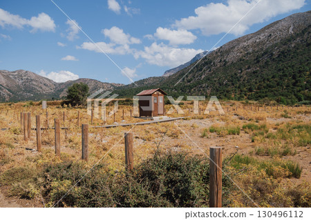 Wooden brown outdoor toilet cabin at the foot of mountains on sunny summer day 130496112