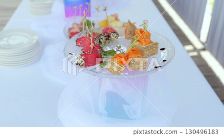 Gourmet appetizers featuring rolled ham, smoked salmon, and delicate bites artfully plated on glass, highlighting elegant catering presentation 130496183