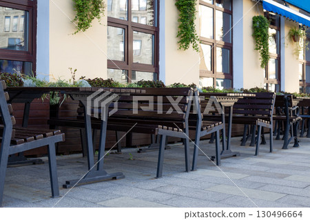 Modern outdoor seating arrangement with benches and tables, accented by decorative planters. The minimalist design creates an inviting space for social gatherings in urban environments Modern outdoor seating arrangement with benches and tables, accented by decorative planters. The minimalist design creates an inviting space for social gatherings in urban environments 130496664
