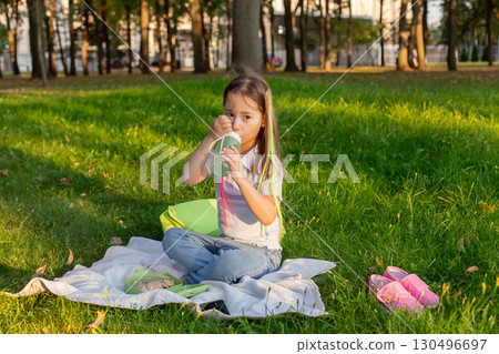 Little girl enjoying picnic in sunny park setting Little girl enjoying picnic in sunny park setting 130496697
