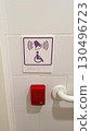 Accessible emergency alert button with braille sign on white tiled wall 130496723