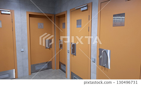 Orange restroom doors with accessibility signs in modern public facility 130496731