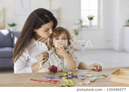 Mother and son playing game with English alphabet letters, mom and boy sitting at home table 130496977