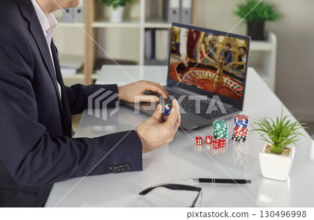 Close-Up Of Man Playing Online Casino With Chips 130496998