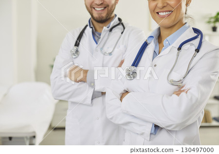 Unrecognizable woman and man doctors keeping hands crossed, wearing white medical coats 130497000