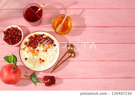 Granular fresh cottage cheese with pomegranate seeds, raisins, honey and juice on a sunny table, detox diet and natural nutrition concept, healthy lifestyle advertising, baby food. Healthy breakfast 130497230