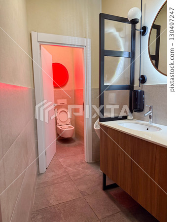 Modern bathroom interior with sink, mirror and glowing circular red light. Hygiene, cleanliness, and contemporary design combined with functional furnishing and bright atmosphere. Modern bathroom interior with sink, mirror and glowing circular red light. Hygiene, cleanliness, and contemporary design combined with functional furnishing and bright atmosphere. 130497247