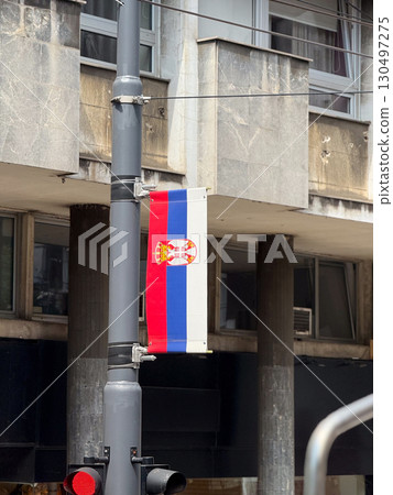 Serbian national flag hanging on a pole near a concrete building. Patriotism, identity, and cultural heritage in urban surroundings. Serbian national flag hanging on a pole near a concrete building. Patriotism, identity, and cultural heritage in urban surroundings. 130497275