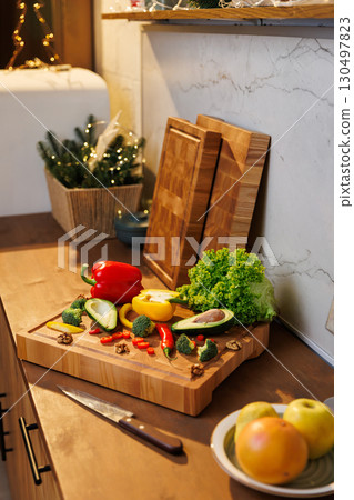 Colorful vegetables and avocado on a wooden board in a cozy festive kitchen 130497823