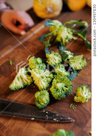 Freshly cut broccoli florets on a wooden board with a kitchen knife, rustic cooking concept Freshly cut broccoli florets on a wooden board with a kitchen knife, rustic cooking concept 130497830