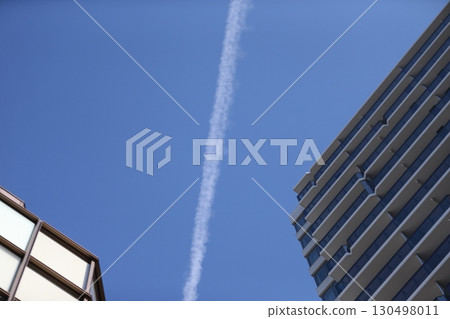 Image of a contrail and an apartment building 130498011