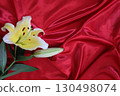 Lilies on red satin fabric background 130498074