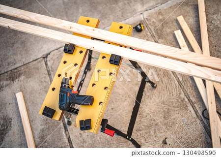 Electric drill and wooden plank on a table outdoors 130498590