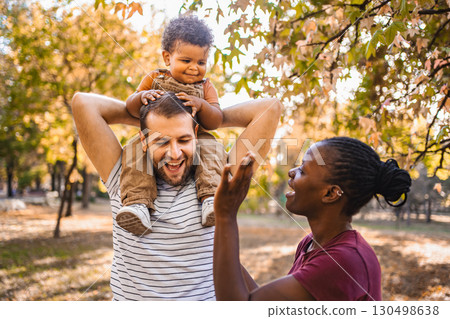 Boy in the arms of his parents in the park Boy in the arms of his parents in the park 130498638