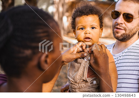 Boy in the arms of his parents in the park Boy in the arms of his parents in the park 130498643