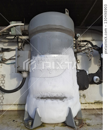 A heavy-duty refrigerator motor covered in frost is seen in an industrial setting, indicating low operational temperatures. A heavy-duty refrigerator motor covered in frost is seen in an industrial setting, indicating low operational temperatures. 130498903