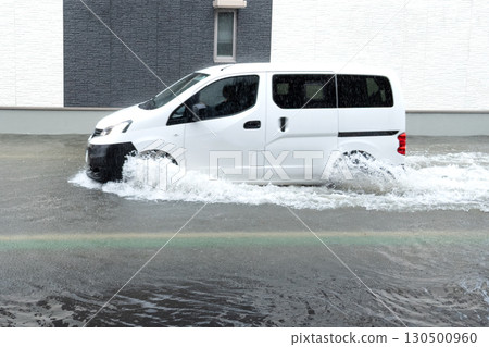 一輛汽車行駛在被水淹沒的道路上，濺起水花。 130500960