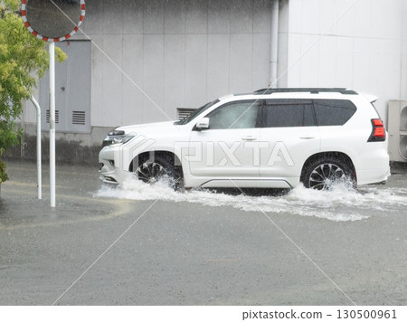 一輛汽車行駛在被水淹沒的道路上，濺起水花。 130500961
