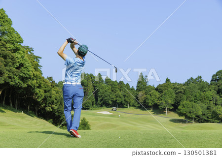 一個人在美麗的新鮮綠樹環繞的發球區上擊球 一個人在美麗的新鮮綠樹環繞的發球區上擊球 130501381