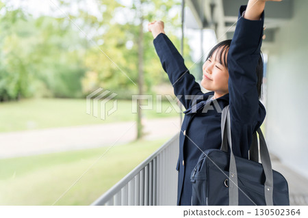 Elementary school, junior high school, and high school girls in uniforms taking a deep breath in a school building 130502364