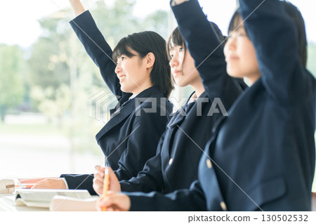 Active elementary school students, junior high school students, high school students, and high school girls (friends) in uniforms raising their hands during class in a school classroom 130502532