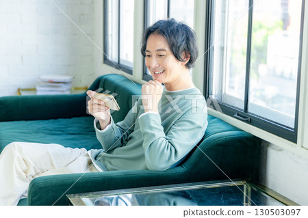 man using smartphone on sofa man using smartphone on sofa 130503097