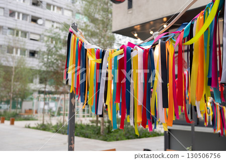 Vibrant colorful ribbons decorating outdoor urban setting with trees and buildings 130506756