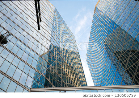 Modern glass skyscrapers reflecting blue sky in urban landscape Modern glass skyscrapers reflecting blue sky in urban landscape 130506759