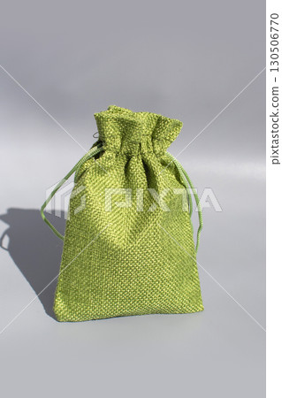 Green textured linen drawstring pouch against gray background Green textured linen drawstring pouch against gray background 130506770