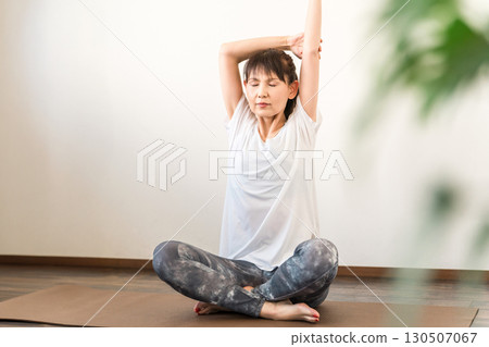 A woman practicing yoga in a yoga studio or yoga class (instructor/yoga teacher) 130507067