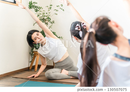 Yoga teacher/instructor teaching yoga in a yoga class/pilates and female student Yoga teacher/instructor teaching yoga in a yoga class/pilates and female student 130507075