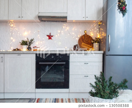 Festive White Kitchen with Garland Lights and Greenery Decoration at Christmas Holiday Season 130508388
