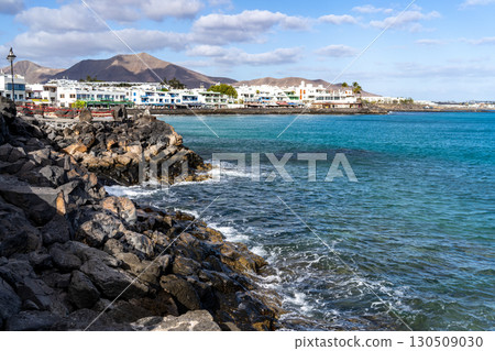 Coastal scenery of Lanzarote featuring vibrant turquoise waters, white buildings, and a rugged, rocky shoreline. Coastal scenery of Lanzarote featuring vibrant turquoise waters, white buildings, and a rugged, rocky shoreline. 130509030