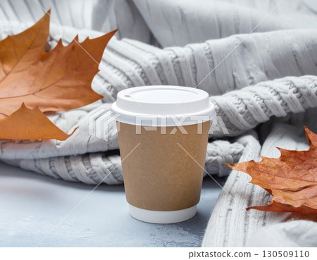 Craft Paper Coffee Cup with White Lid on Gray Table with Knit Scarf and Orange Autumn Leaves Craft Paper Coffee Cup with White Lid on Gray Table with Knit Scarf and Orange Autumn Leaves 130509110